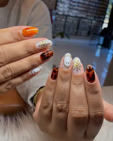 Halloween nail art with gold spider webs, ghosts and tortoiseshell on almond nails